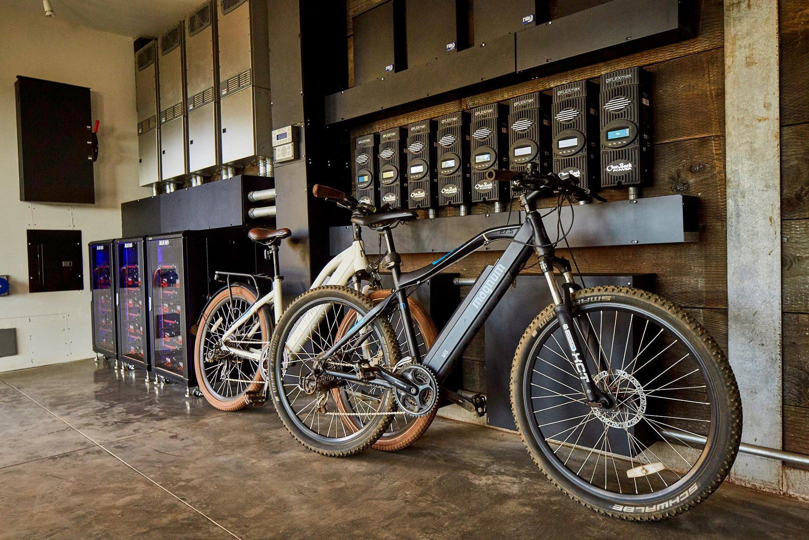 The mechanical bay: a rack of OutBack inverters and battery banks feeding the off-grid system, with two e-bikes parked against reclaimed-wood cladding
