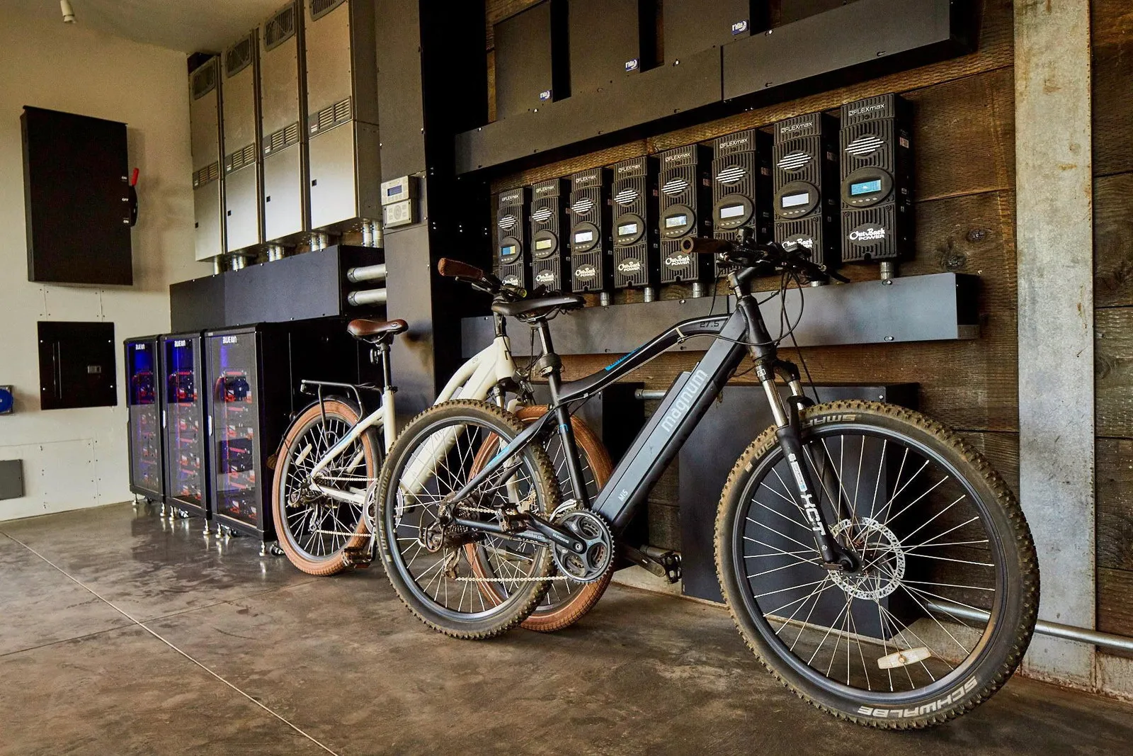 The mechanical bay: a rack of OutBack inverters and battery banks feeding the off-grid system, with two e-bikes parked against reclaimed-wood cladding